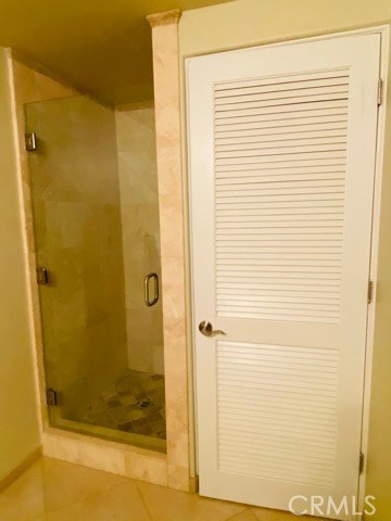 Hallway Bathroom with Glass Enclosed Shower & Shuttered Door to Washer/Dryer.