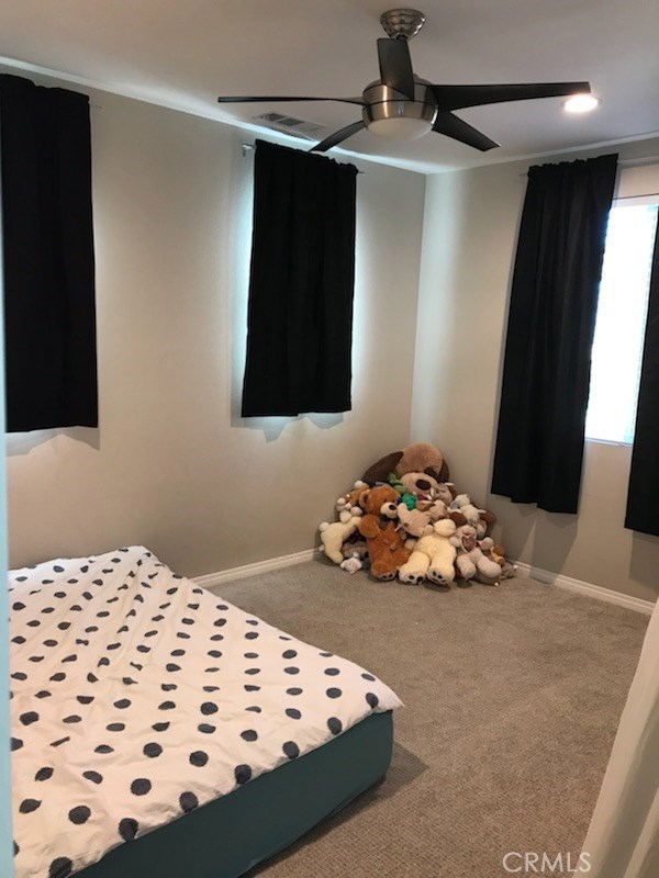 Bedroom 2 with ceiling fan and many windows.