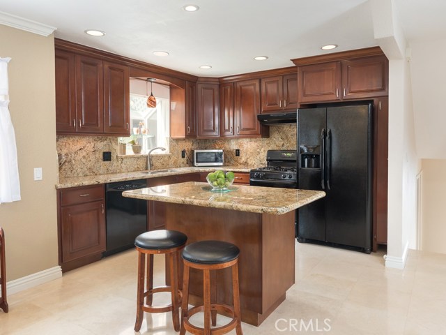 Beautifully remodeled kitchen has custom cherry cabinets, Golden Beach granite counters, recessed lighting, and garden window.