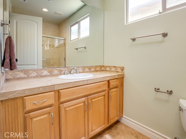 Full bath on entry level with stone flooring and counters and maple cabinetry.