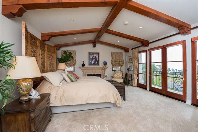 Large master suite has pretty fireplace, wall of windows and French doors to the view balcony, and a sitting area.