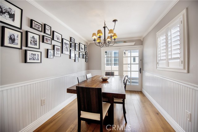 Charming dining room with gleaming wood floors, wainscoting, french doors to the patio