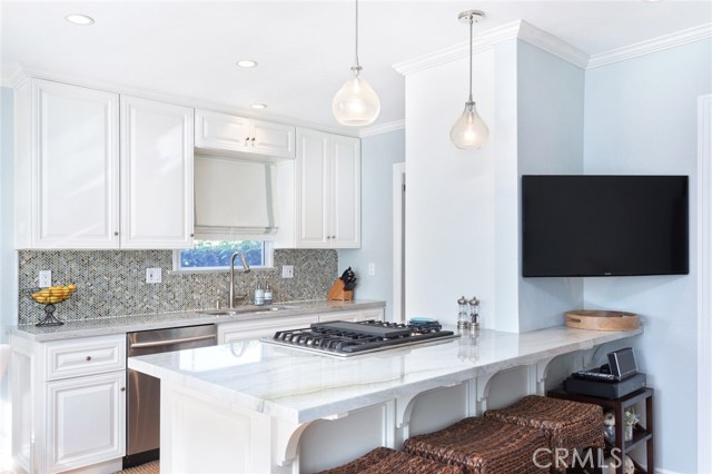 Open kitchen features quartz counter tops, pendant lighting, new cabinets.