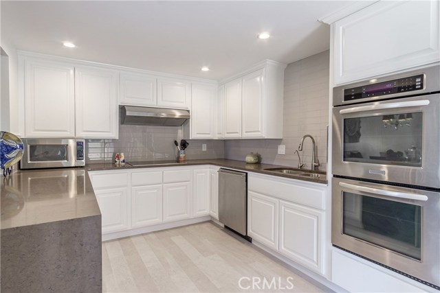 Updated kitchen with waterfall stone island, stainless appliances, new flooring, subway tiles
