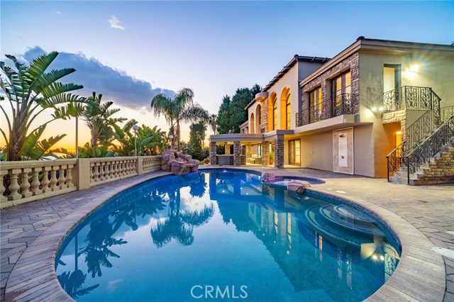 Another view of the backyard with pool, waterfalls, several conversation areas, covered patio, built in bar-b-que and full size tennis court!