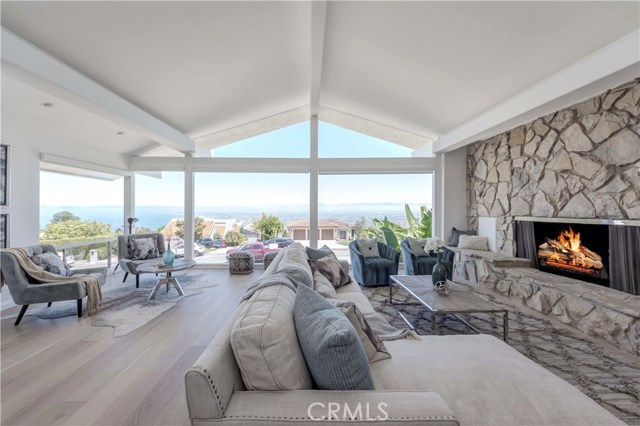 Open floor plan, master living room with ocean view, stone fireplace, new wood flooring, and Hunter Douglas window shades with a remote control.