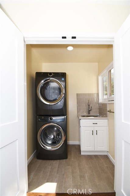 Stackable washer/dryer and laundry sink hidden behind doors near the kitchen for easy access