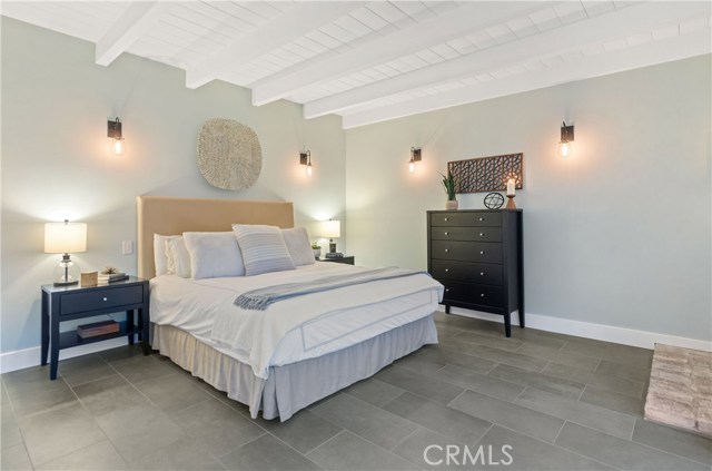 The primary bedroom suite is tranquil and complete with open beamed ceilings, decorative lighting, and thoughtfully spacious closet and storage.