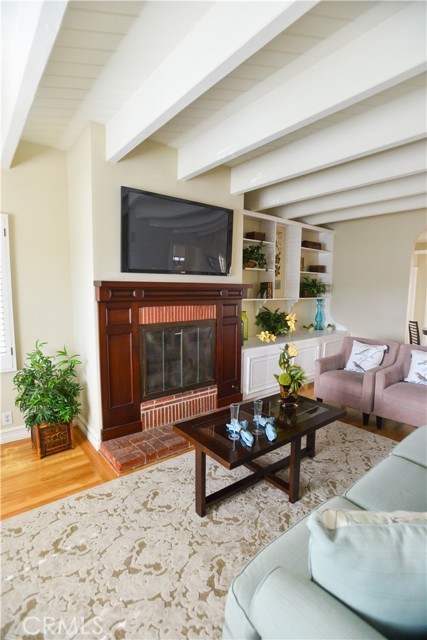 Living room with fireplace, beamed ceilings and hardwood floors and built-in bookcases.