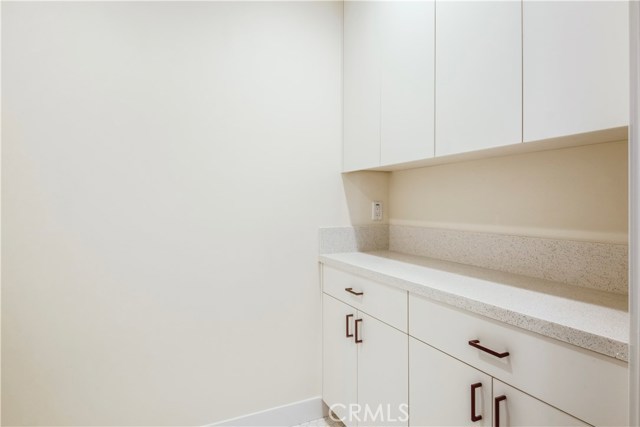 Laundry room with built in cabinets, quartz countertop, and honeycomb tile floors