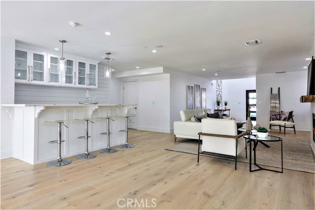 Adjoining the Living Room, there is Large Entertainment Bar featuring lots of Storage Cabinets, Ship Lap Siding and Thick Slab Carrara Caesarstone counter surface