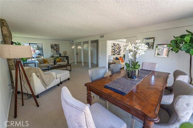 View looking back towards front door entry. Kitchen & den area is through that doorway to left of orchid on dining table where you see sofa w/ orange pillow.