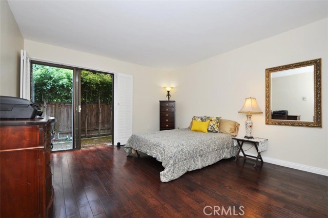 A glimpse through the window to the back brick patio and garden with mature trees.