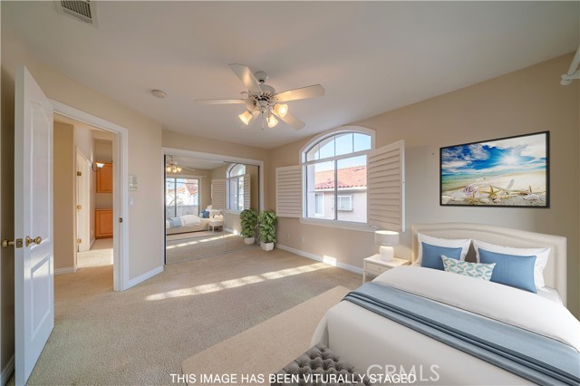 Bedroom featuring plantation shutters, ceiling fan with access to outdoor deck and city lights view