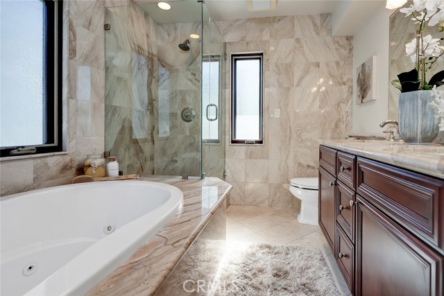 Master bathroom with dual sink countertop and travertine tile throughout.