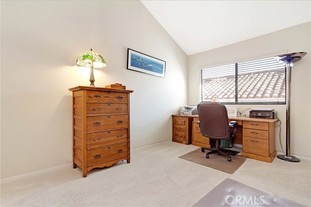 Another bedroom being used as an office with a vaulted ceiling.