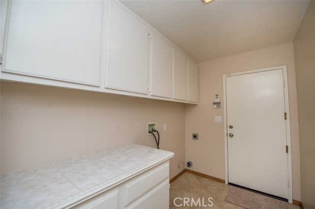 First floor laundry room with hanging cabinets, tiles counter top and ceramic tile floor