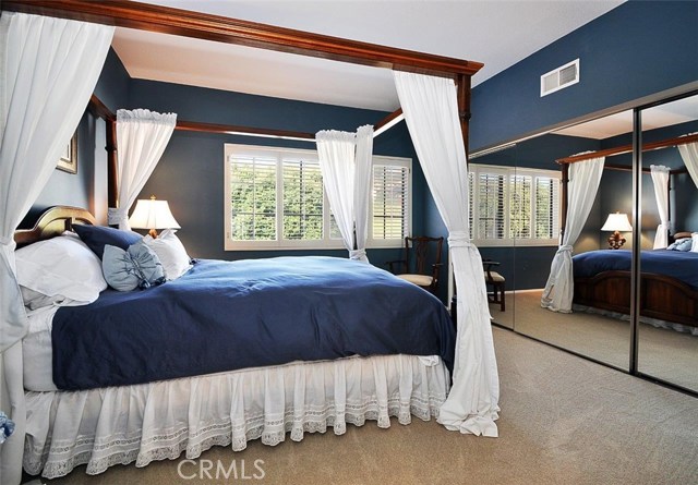 Bedroom 2 with plantation shutters and mirrored closet doors.