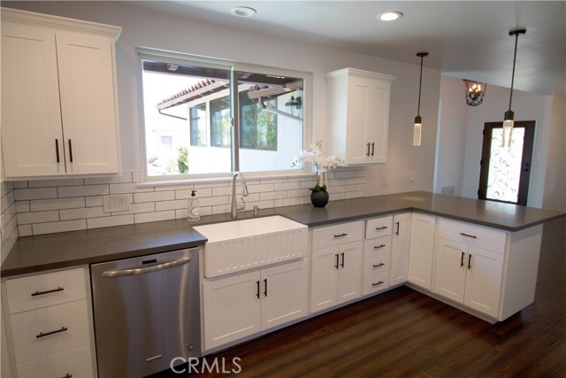 Kitchen boasts white cabinetry w/self-closing drawers & doors, gray quartz counter-tops, Kitchen Aid appliances/including microwave drawer, gorgeous large farm sink, recessed lighting, decorative tiles w/Spanish flair over stove and an Island area which opens to the dining room.