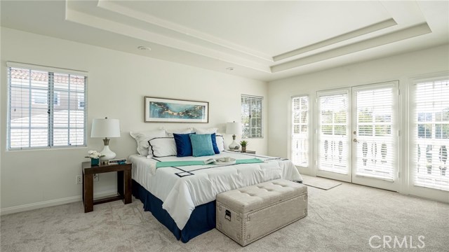 Enormous master bedroom facing french doors that lead out to a balcony on the second floor overlooking the grassy front yard.