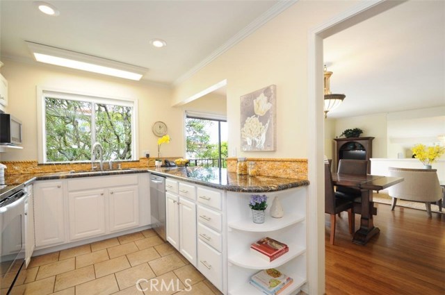 Kitchen has newly painted cabinets, granite counters, stone backsplash and tile floor.