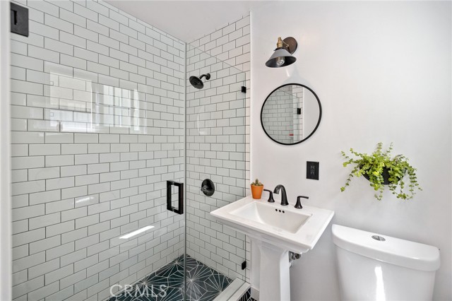 Remodeled downstairs bathroom with subway shower tile and cement tile flooring