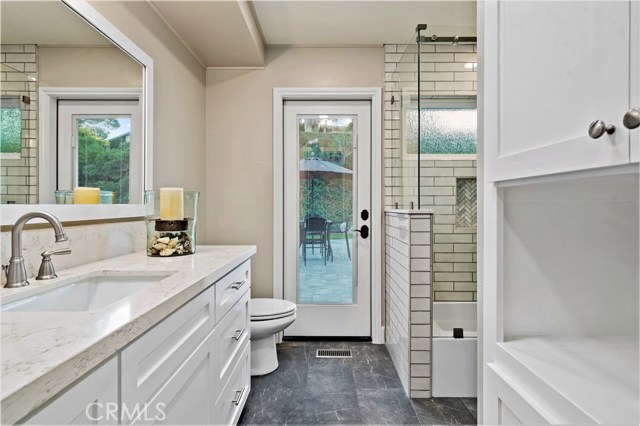Upstairs bathroom with quartz countertops and custom cabinets, tub/shower combination with glass enclosure with access to the pool.