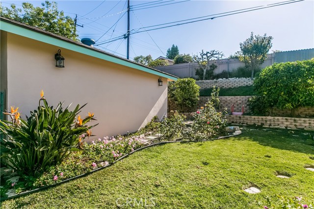 side of garage, grassy yard area, flowers and fruit trees