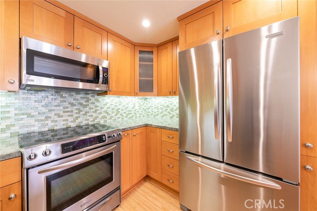 Beautiful SS appliances with full glass tile backsplash.