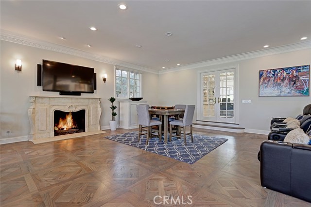 Oversized Living space for gathering as a family, or hosting game nights, centered around a stone fireplace and parquet hardwood floors, with access to the backyard.