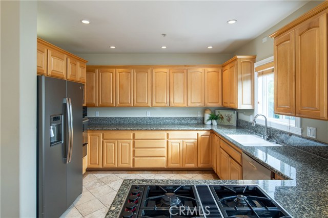 The large kitchen offers granite counters, natural wood cabinetry, newer appliances, and a peninsula with eat-in counter.