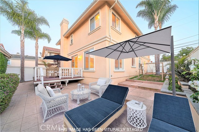 Spacious backyard patio with attached deck and grassy sideyard with gated access to enclosed front yard