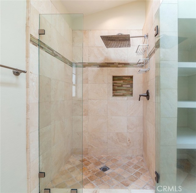 Master shower with frameless glass door and rain shower head.