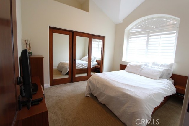 High ceilinged bedroom, naturally lit, with shutter regulation, ceiling fan.