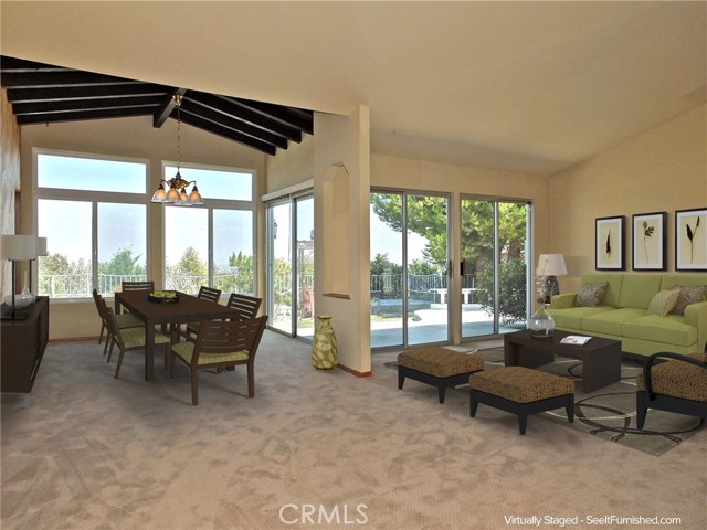 Open floor plan, vaulted ceilings, exposed beams, and views through glass feature in the main living room and dining room.