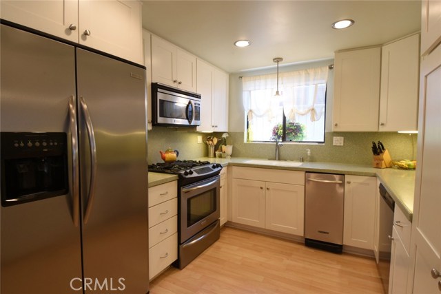 Remodeled kitchen with white shaker cabinets, corian counters, and stainless appliances.