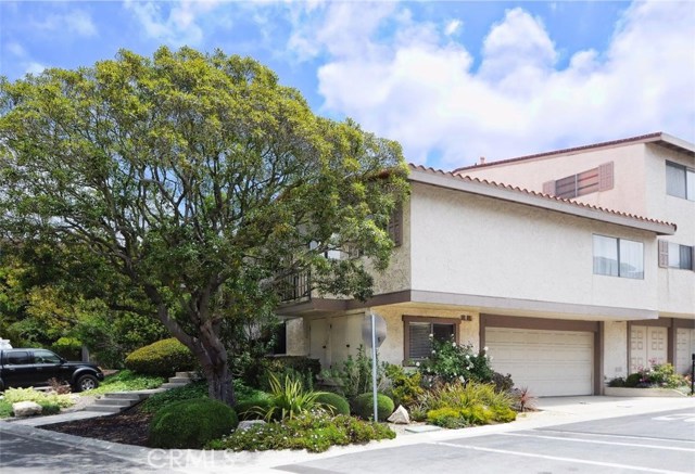 Corner unit with attached two car garage and front entrance, with visitor parking in front.