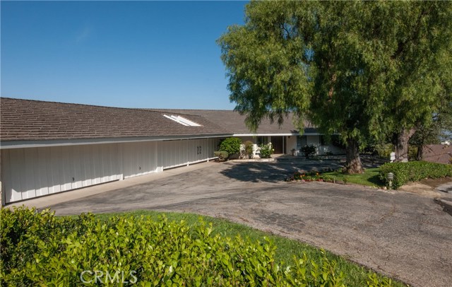 View from the side yard showing the 3 car garage, front of covered patio plus front door - with great circular drive.