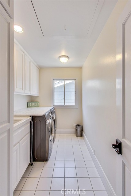 Laundry room with built-in cabinetry and pull down attic access overhead.