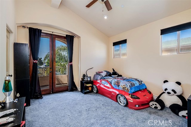 Front bedroom with balcony, vaulted ceilings, ceiling fan, and black out shades on windows.