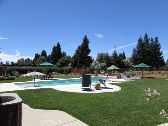 View from other side of backyard.  Newer concrete around pool where picnic table and chairs which make entertaining by the pool easier.