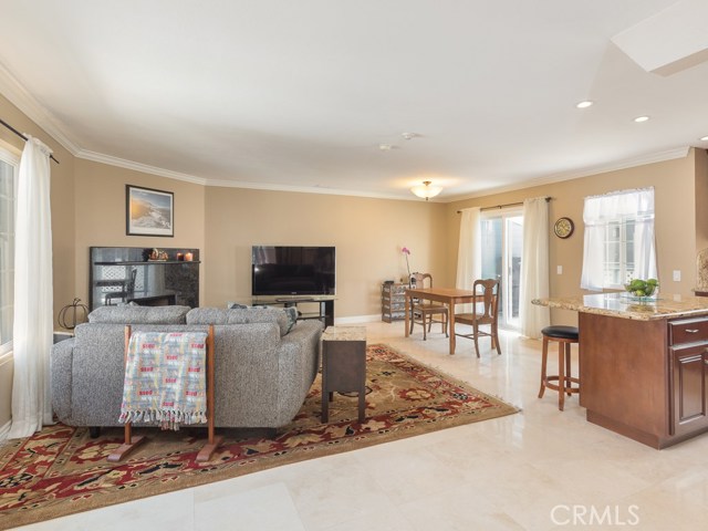 Main level has great room with living, dining, and kitchen spaces all open. Polished travertine floors, recessed lighting, and crown moldings grace this open space.