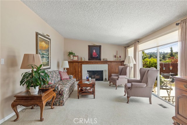 Formal Living Room with cozy fireplace, and sliding glass doors leading to the Patio