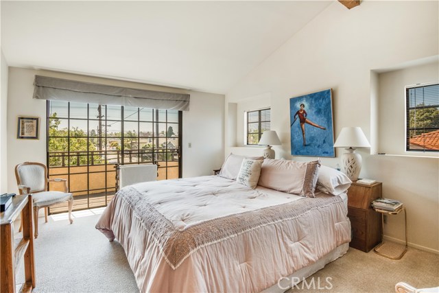 Large master suite has a private balcony with southern views of Palos Verdes. Large sliding doors face south, while there are more windows facing west. Note high vaulted open-beam ceilings.