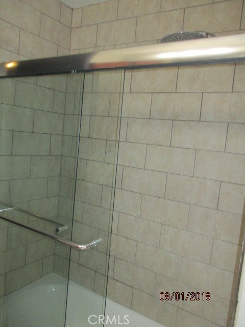 Full updated tiled tub/shower combination with glass enclosure.