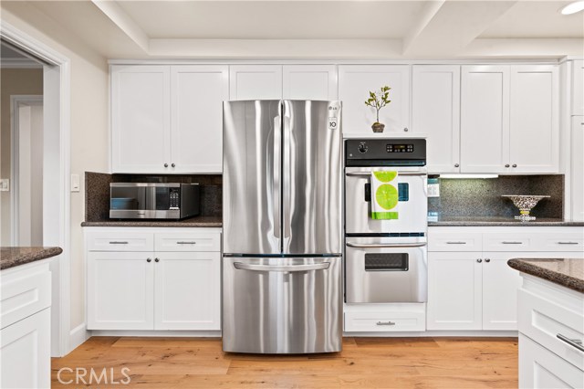 Kitchen with white shaker cabinets, engineered wood floors and new oven.