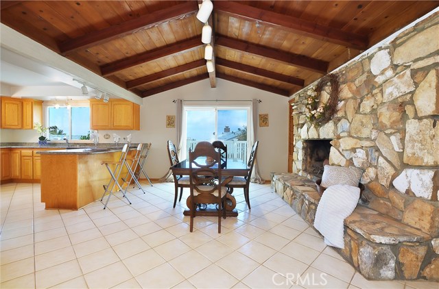 Family/dining room with vaulted wood beam ceiling and fireplace