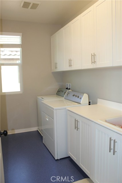 Large laundry room with many cabinets and sink.