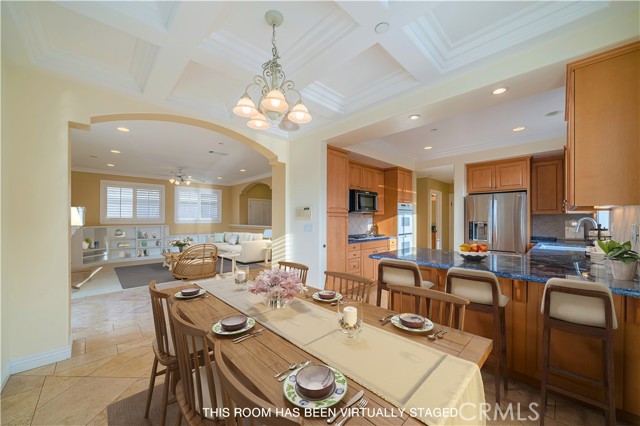 Dining area with coffered ceiling, breakfast counter seating, lovely arched entry to living room