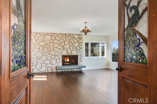 A different perspective on the living room reflecting the custom stained glass entry doors, new real wood floors, some of the new windows, new lighting and inviting fireplace